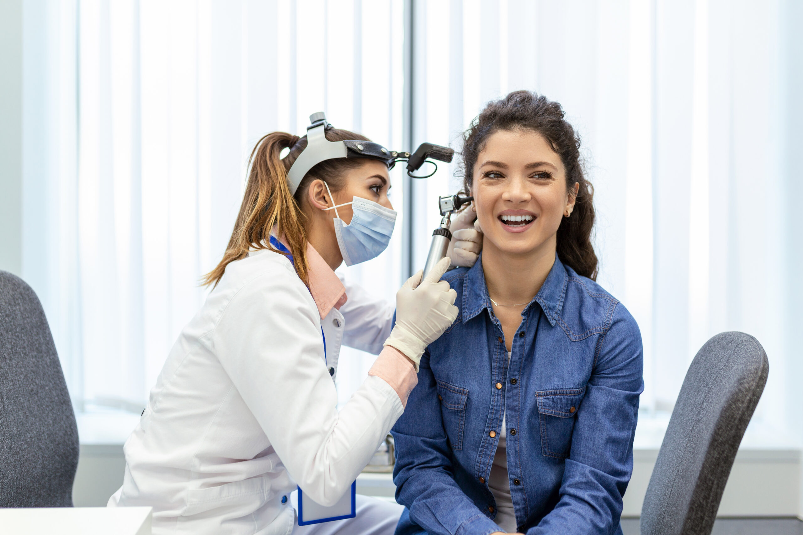 Hearing exam. Otolaryngologist doctor checking woman's ear using otoscope or auriscope at medical clinic.