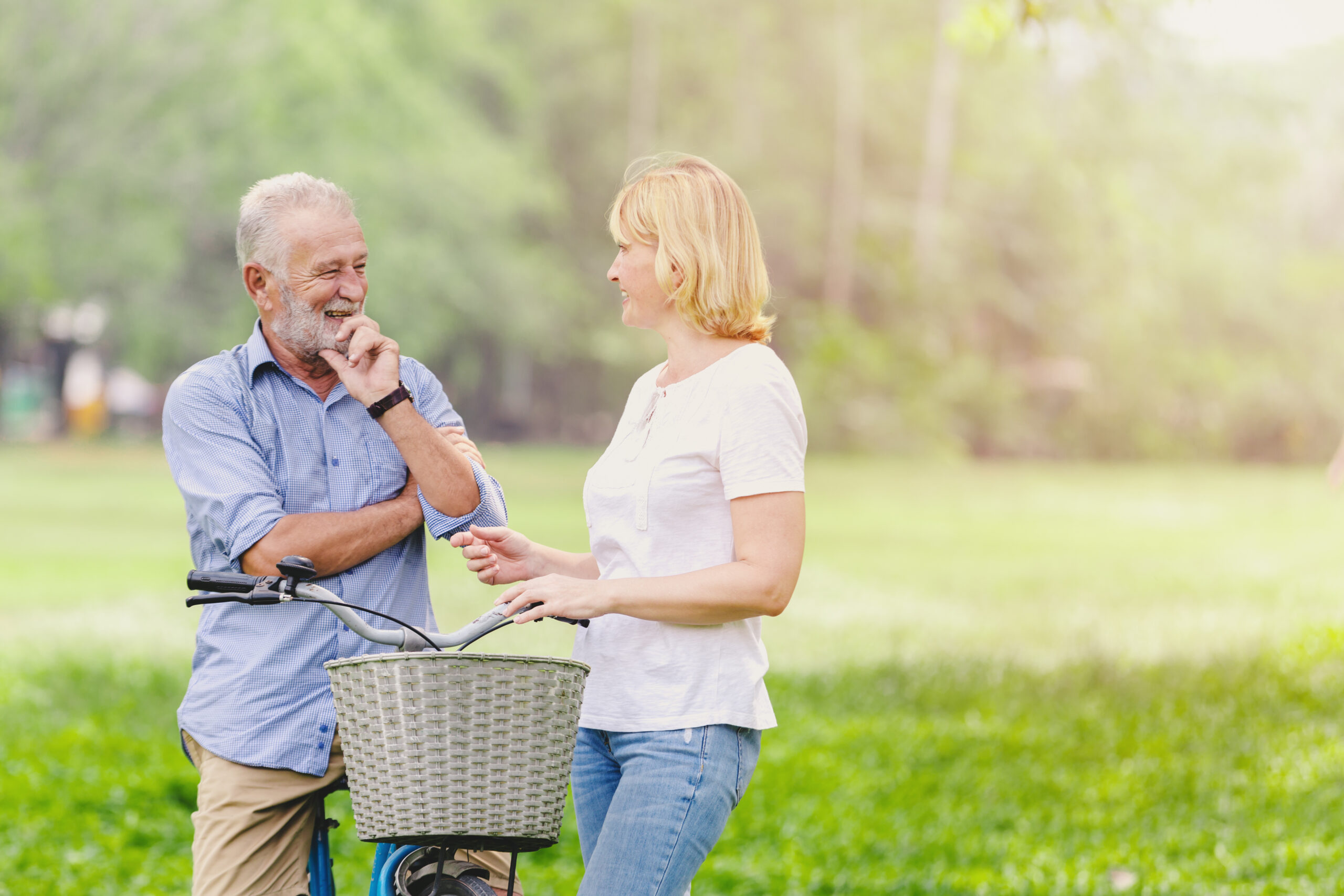 Senior elderly couple standing talking their bike in park