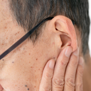 man with hand on ear in discomfort