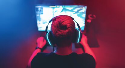 Background professional gamer playing tournaments online games computer with headphones, red and blue.