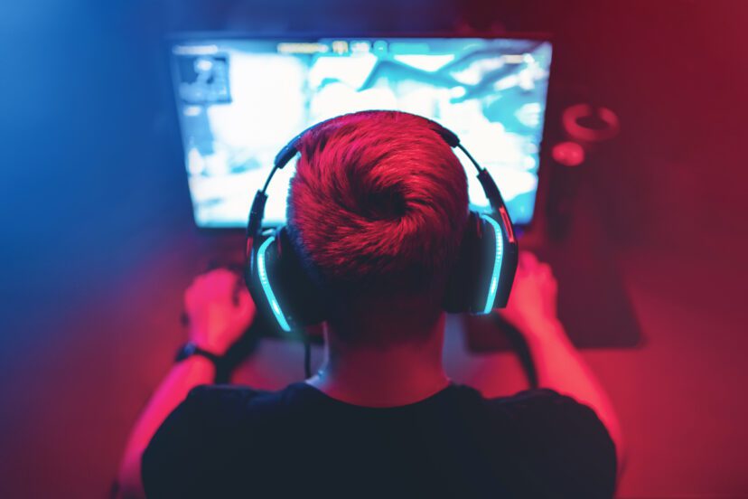 Background professional gamer playing tournaments online games computer with headphones, red and blue.