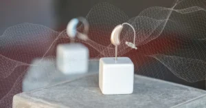 A modern beige hearing aid displayed on a white stand, symbolising the sleek design and technology innovations in 2025